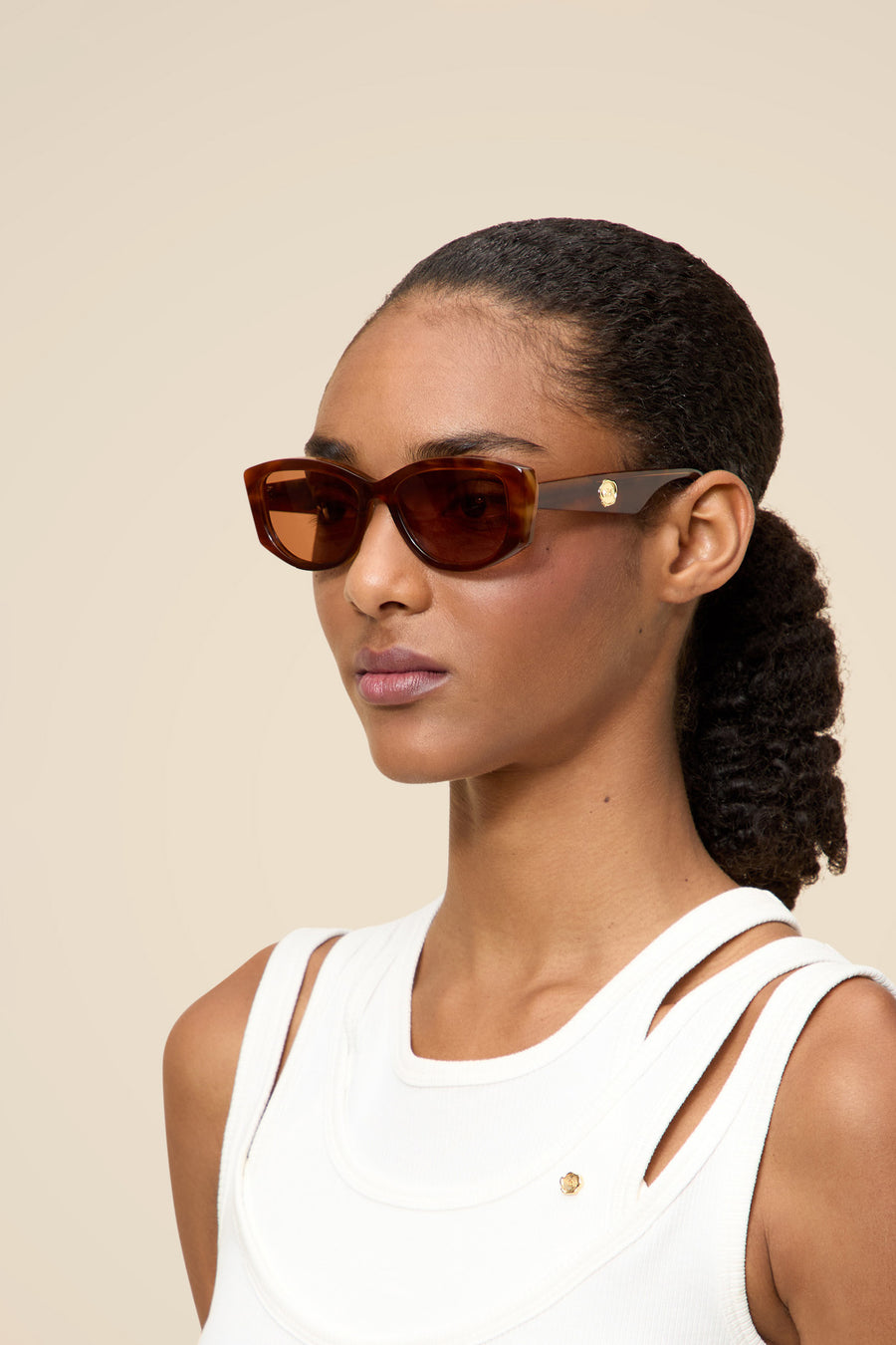 Sleek rectangular tortoiseshell sunglasses with gold detail on arms, paired with a chic white sleeveless top.