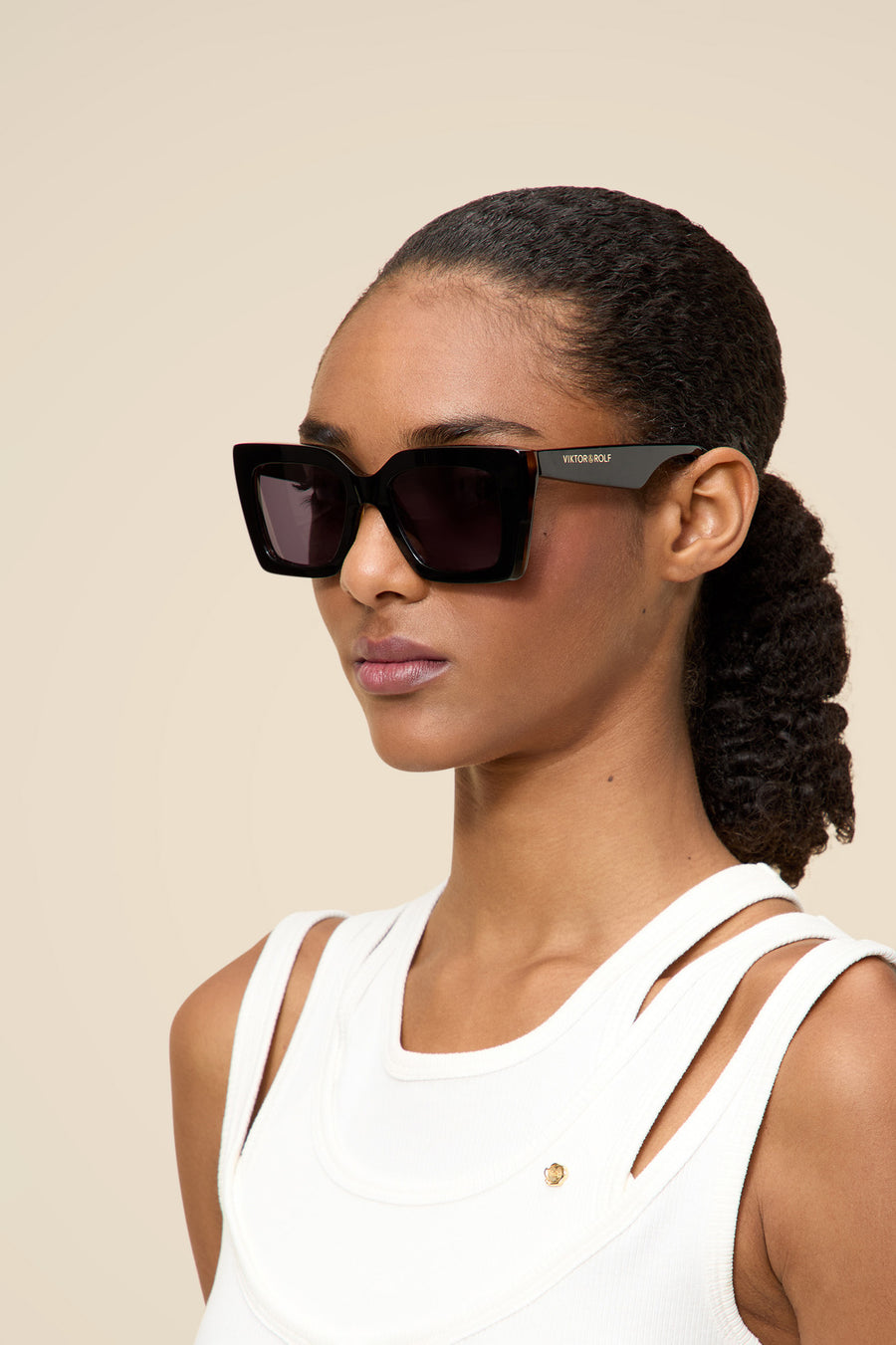 Elegant oversized black sunglasses with sleek acetate frames, worn with a modern white sleeveless top.