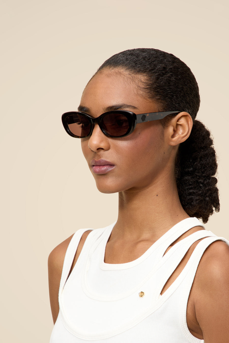 Sleek black rectangular sunglasses paired with a chic white sleeveless top, set against a neutral background.