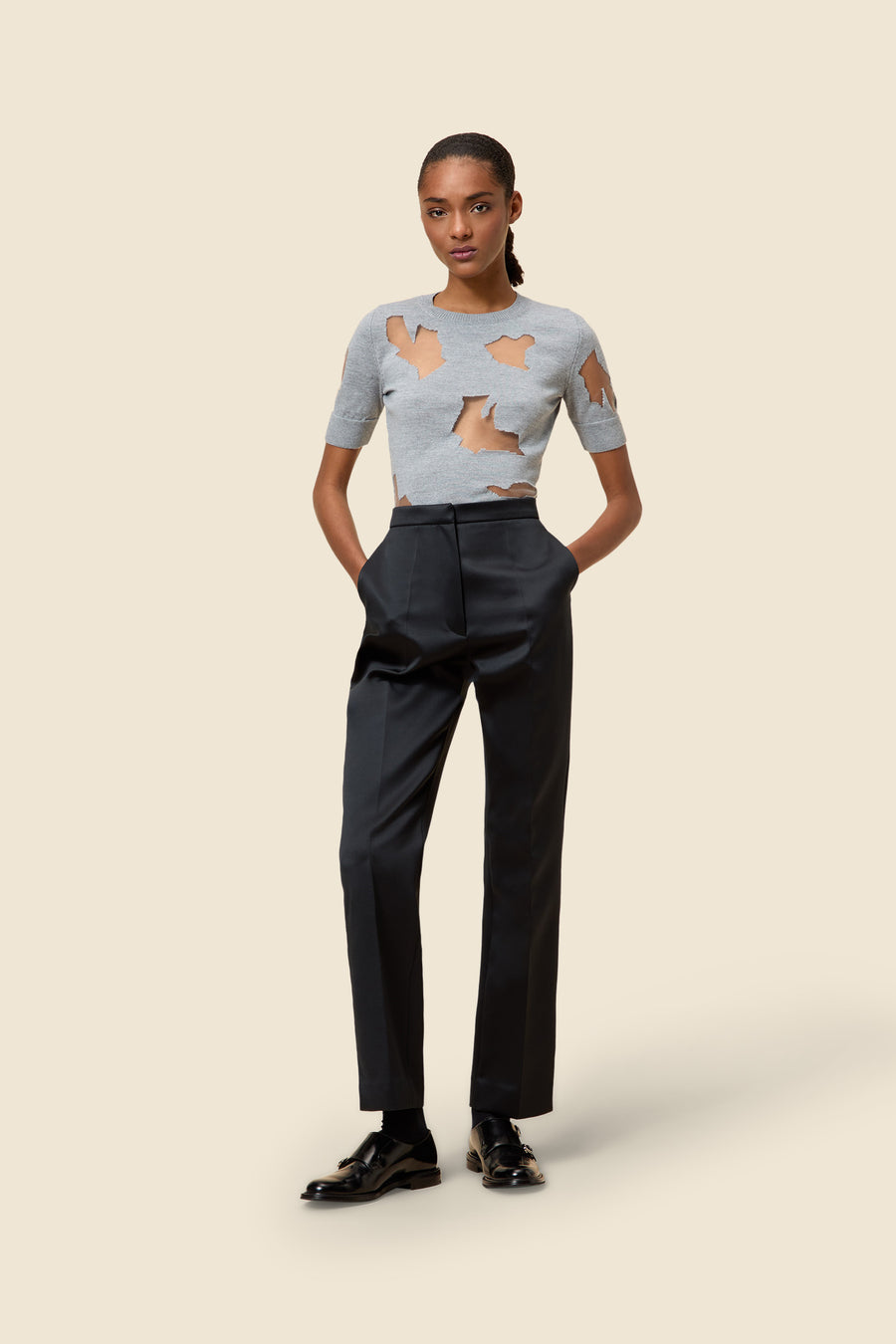 Elegant outfit featuring a grey cut-out sweater paired with tailored high-waisted black trousers and polished black shoes.