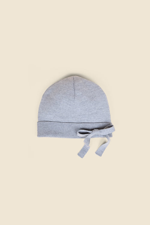 Soft grey baby hat made of cozy knit fabric, featuring a ribbed turn-up edge and delicate bow detailing on a neutral backdrop.