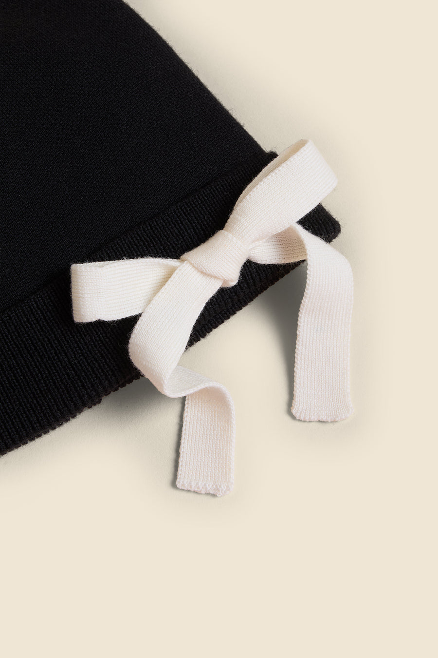 Black knit fabric hat featuring a contrasting white ribbon bow detail, elegantly crafted for a chic and stylish look.