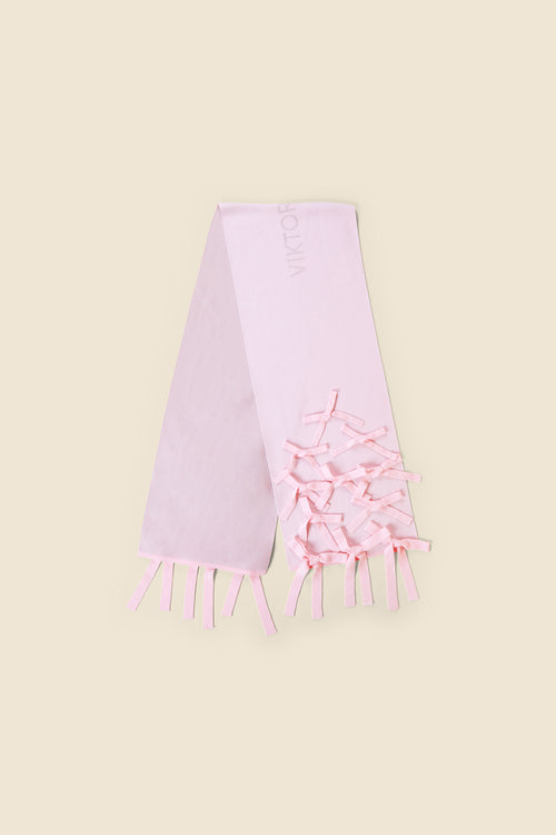 Elegant pink satin scarf adorned with delicate bow details, featuring a refined fringe trim on a neutral background.