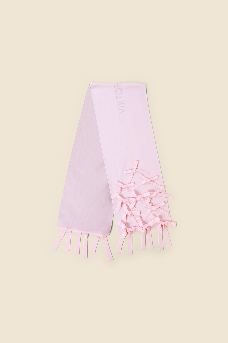 Elegant pink satin scarf adorned with delicate bow details, featuring a refined fringe trim on a neutral background.