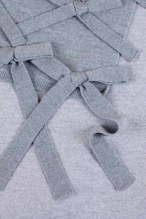 Soft gray knitted sweater detail featuring elegant ribbon bows intricately tied across the textured fabric.