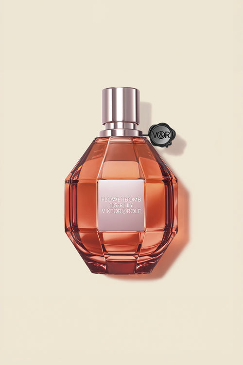 A faceted bottle of Flowerbomb Tiger Lily Eau de Parfum by Viktor & Rolf, in amber tones, exuding a floral aroma for women.