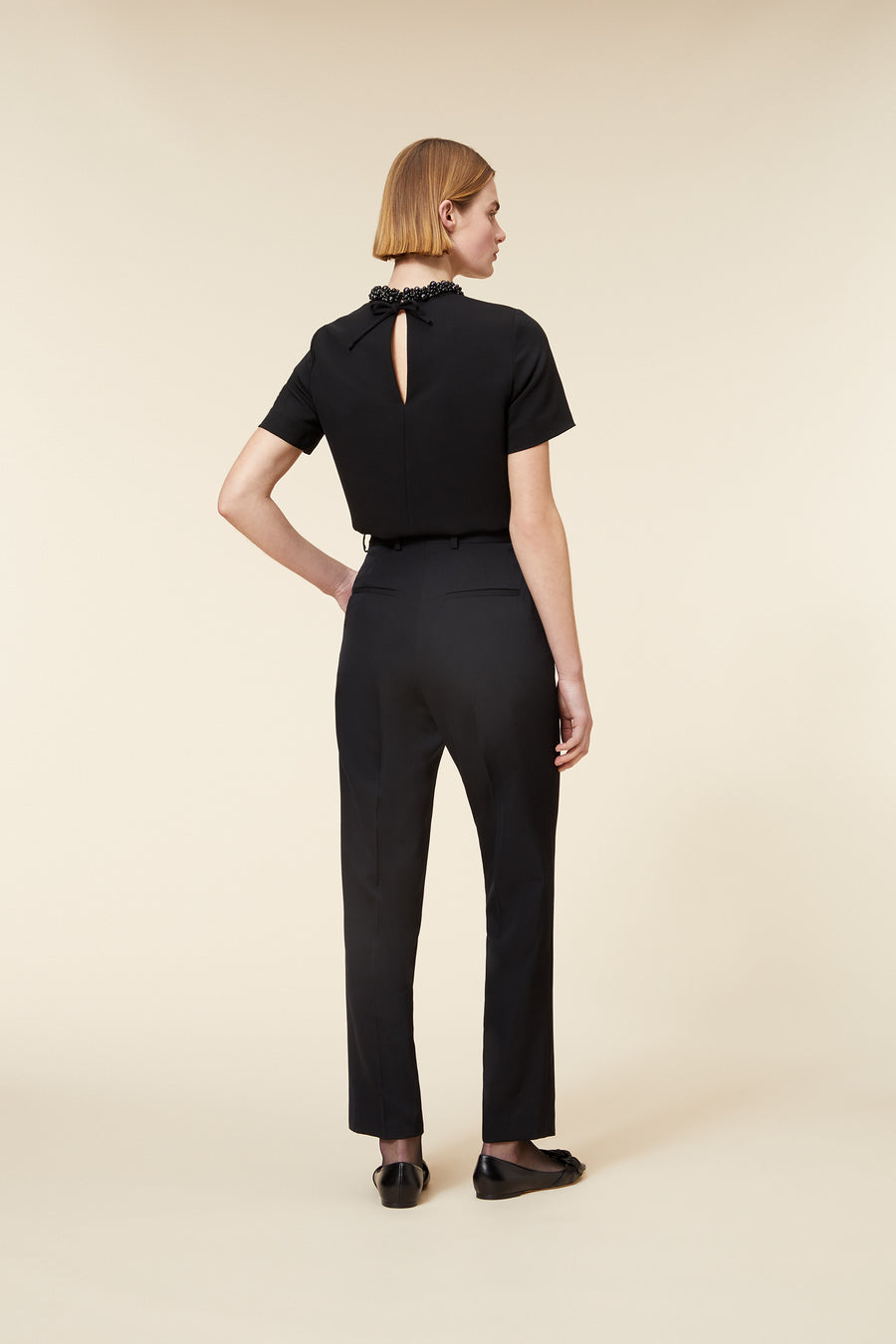 Elegant black tailored jumpsuit with a delicate back cutout and a high neckline adorned with intricate bead detailing.