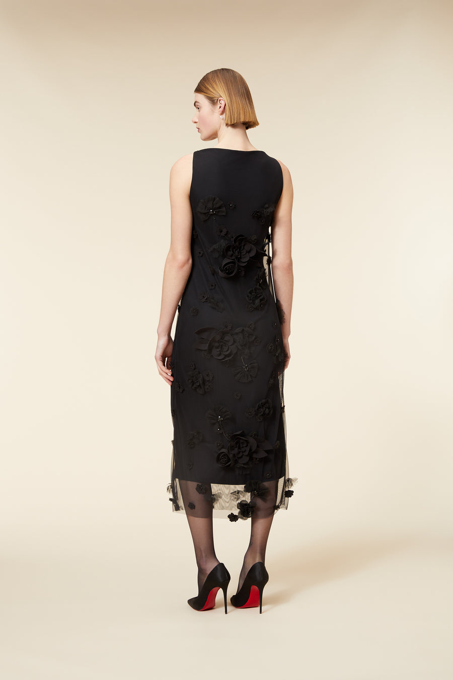 Elegant black floral dress with sheer hem, 3D floral appliqués, paired with black high heels with red soles.