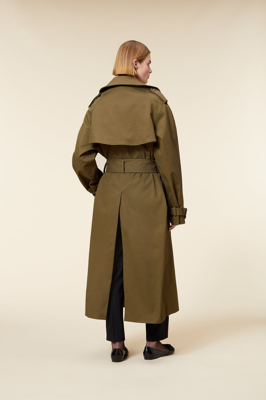 Olive green trench coat with a wide belt and shoulder epaulets, featuring a stylish back vent for added movement.