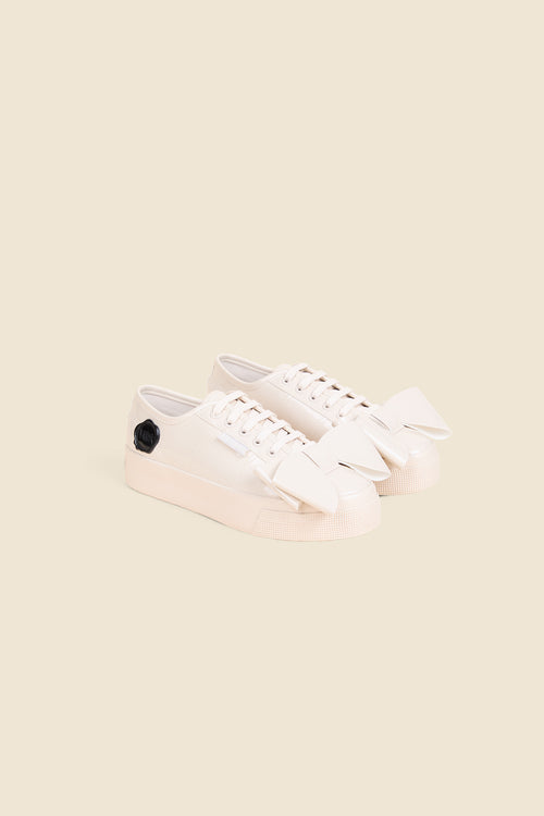 Stylish cream sneakers featuring oversized bows and a black flower accent, perfect for adding flair to casual outfits.