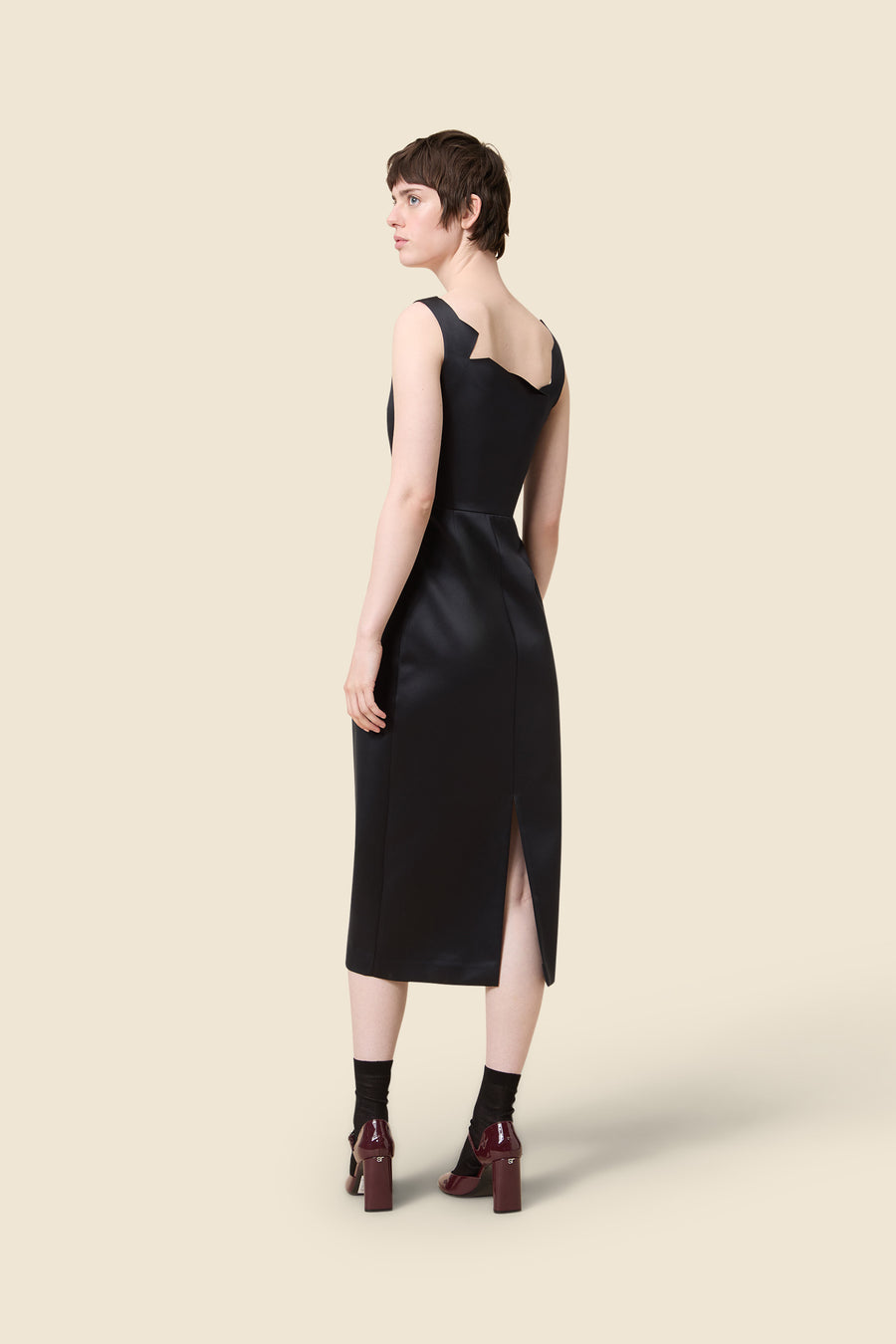 Elegant black satin dress with unique neckline and sleek silhouette, featuring a stylish back slit for a sophisticated look.