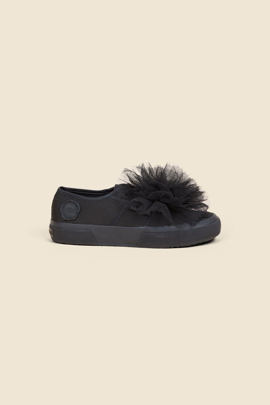 Black sneaker featuring a large tulle flower accent on a smooth canvas base, offering a stylish and playful design.