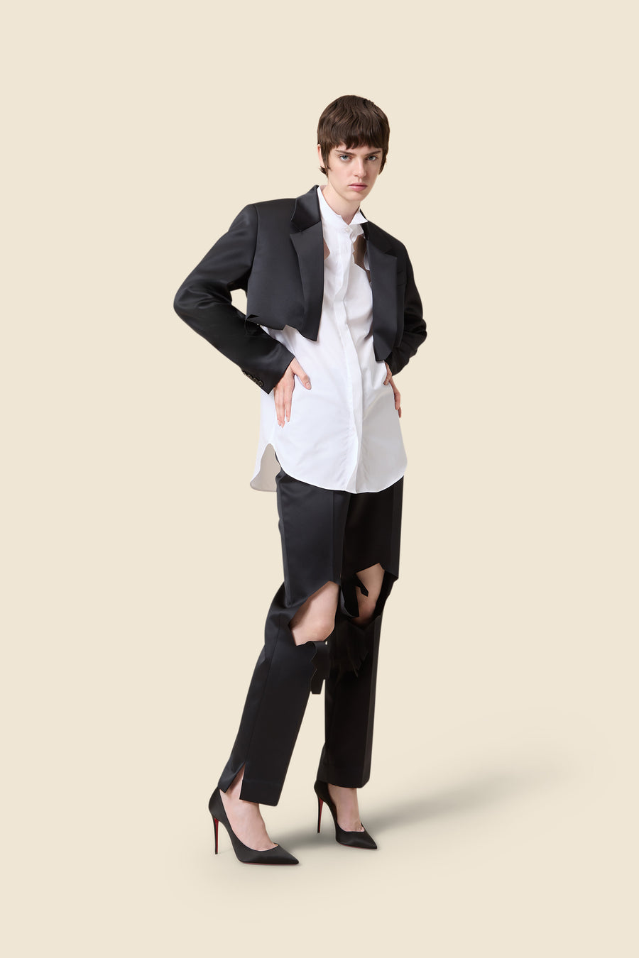 Chic tailored black tuxedo jacket paired with a crisp white shirt, featuring uniquely styled cut-out black trousers.