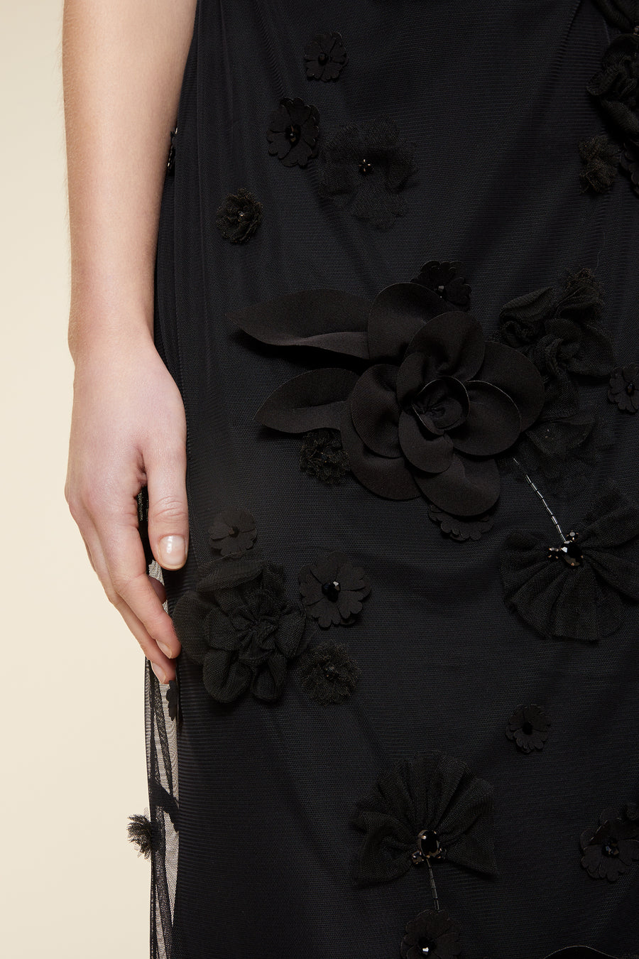 Close-up of a detailed black evening dress with elegant floral appliqués, highlighting the intricate fabric texture.