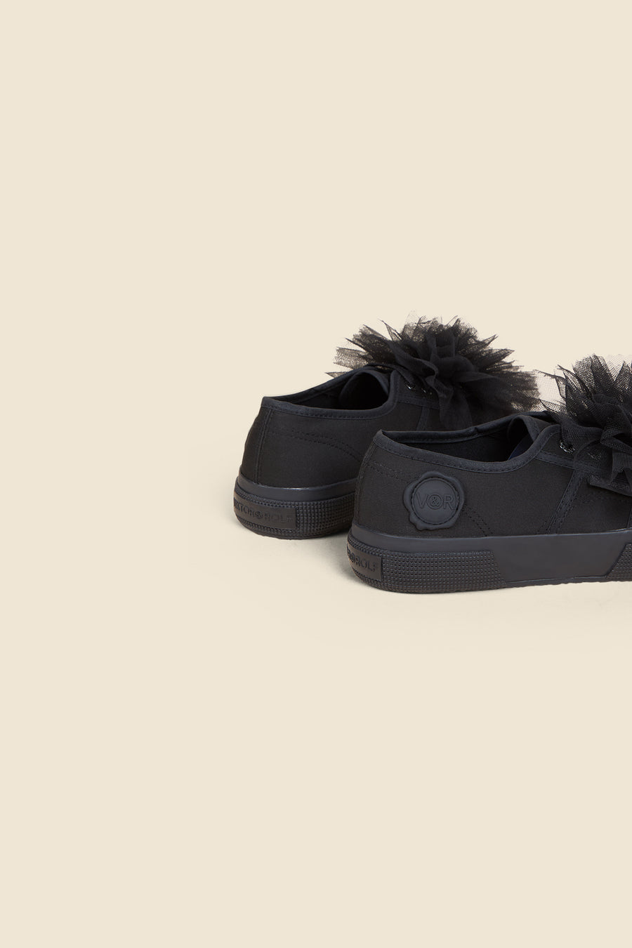 Black canvas sneakers embellished with elegant black tulle flowers, showcasing a playful twist on classic footwear.