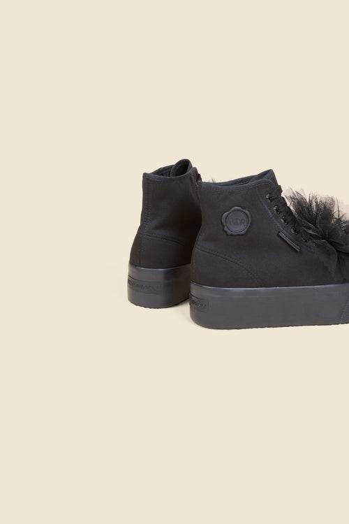 High-top sneakers featuring black canvas with delicate tulle detailing, complete with chunky rubber soles, exuding modern elegance.