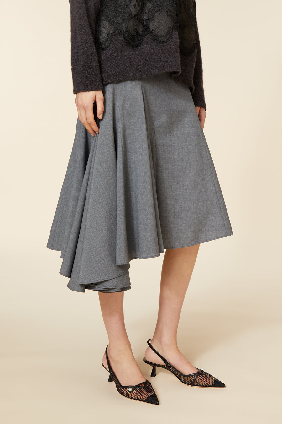 Gray wool A-line skirt with asymmetrical hem paired with black mesh slingback heels and a dark lace-detail sweater.