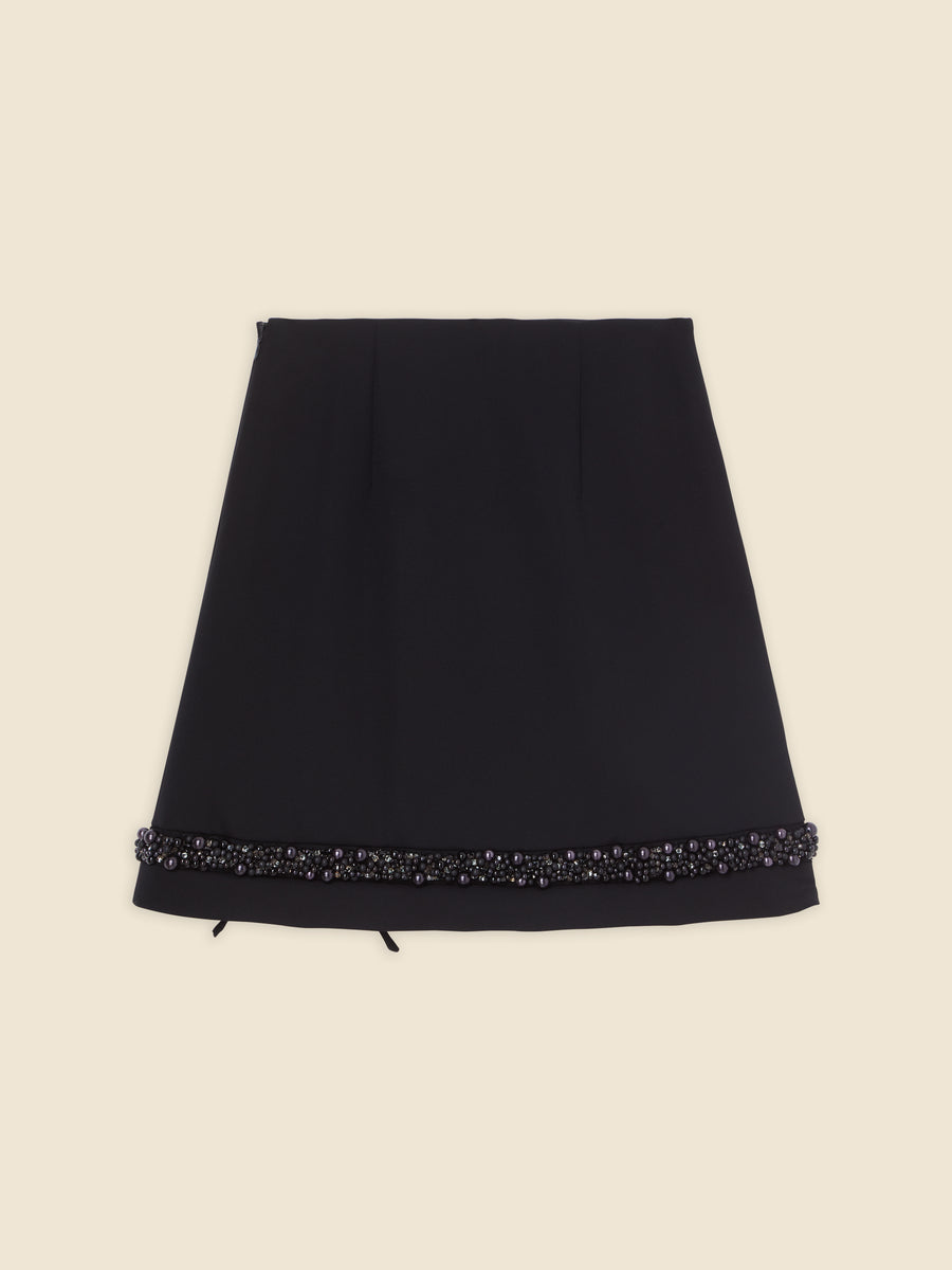 Black A-line skirt adorned with intricate pearl and bead detailing on the hem, creating a chic and elegant look.