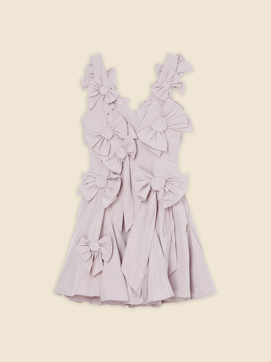 Pastel pink sleeveless dress with multiple large bows, featuring a flared skirt, against a neutral background.