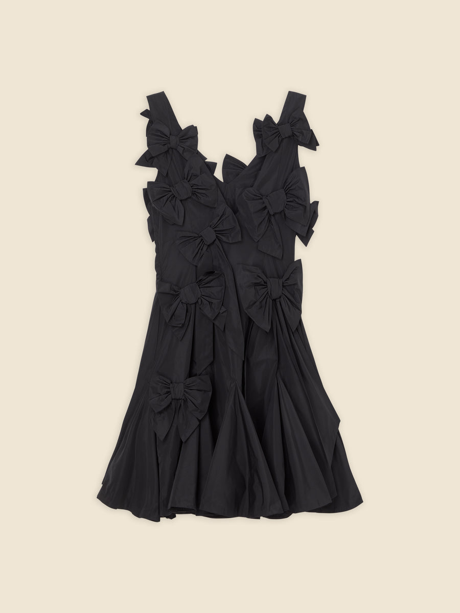 Elegant black dress adorned with multiple oversized bows, creating a charming and sophisticated look against a neutral background.