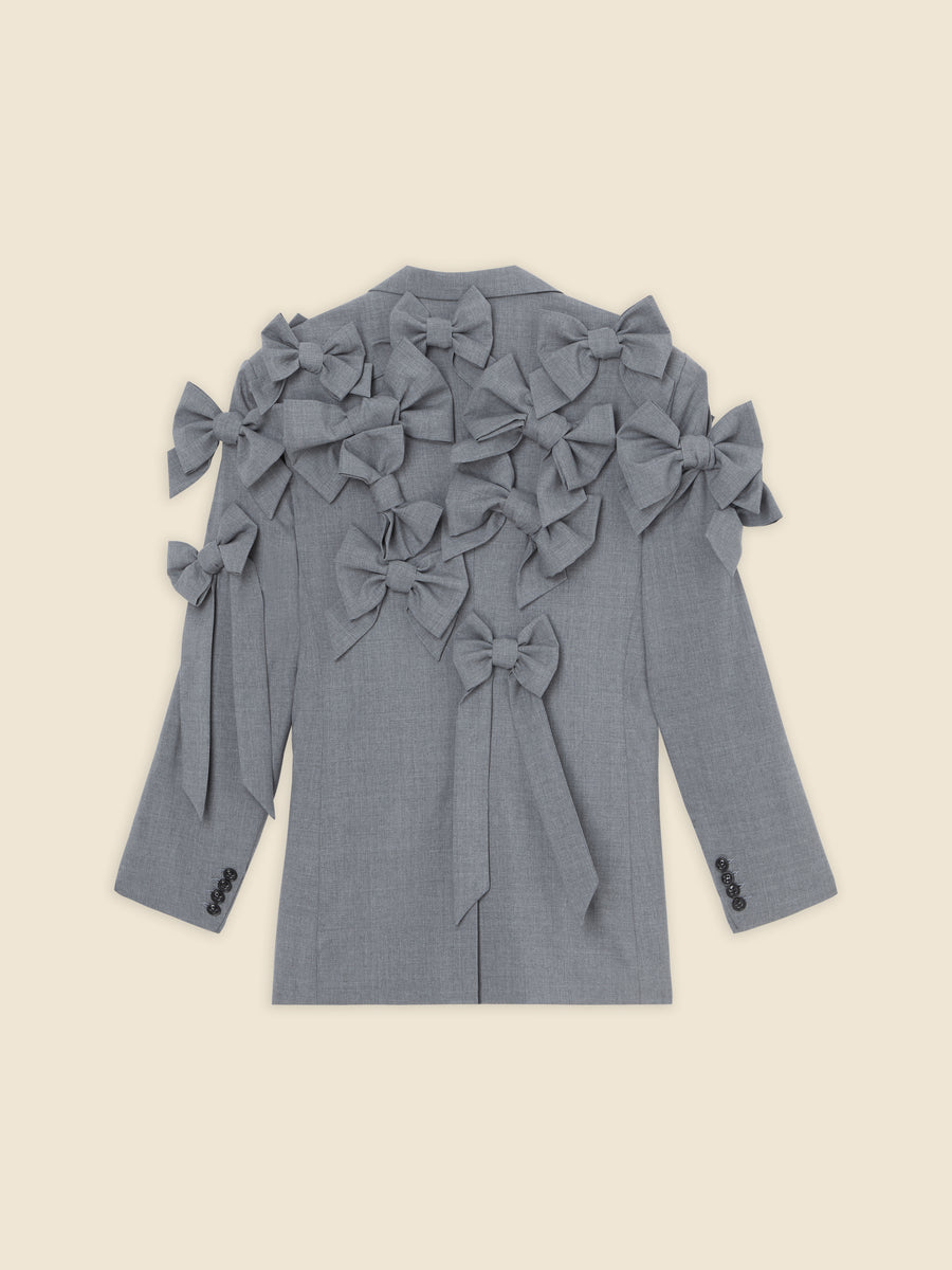 Gray tailored jacket with decorative fabric bows on the back and sleeves, creating a unique and stylish design statement.