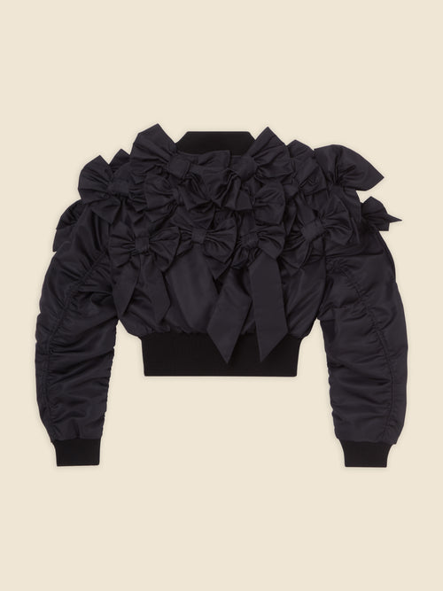 Black satin jacket adorned with multiple elegant bows, featuring structured shoulders and ribbed cuffs in a modern design.