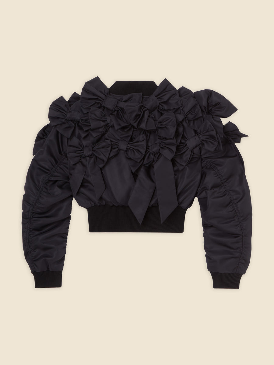 Black satin jacket adorned with multiple elegant bows, featuring structured shoulders and ribbed cuffs in a modern design.