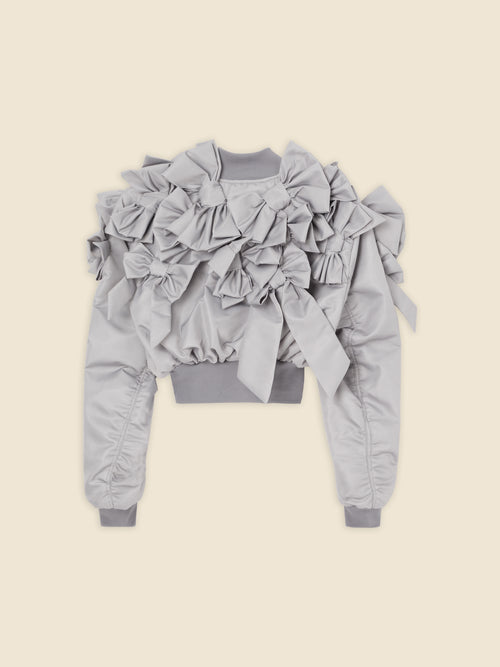 Gray bomber jacket adorned with voluminous ruffles and bows, featuring ribbed cuffs and waistband for a stylish finish.