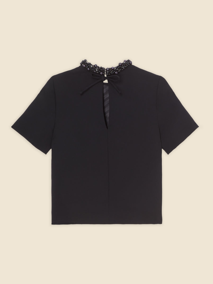 Black short-sleeve blouse with beaded collar and keyhole neckline detail on a plain light-colored background.