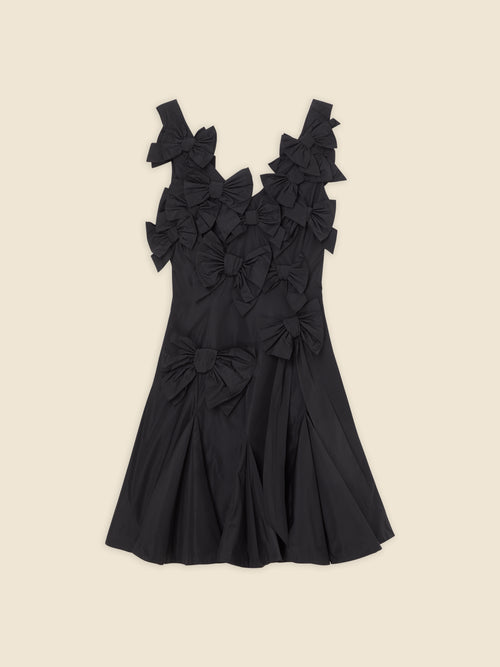 Black dress with multiple oversized bow embellishments, featuring a sleeveless design and a flowing skirt for an elegant look.