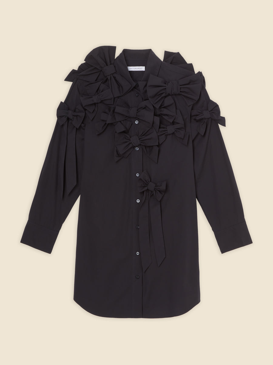 Black long-sleeve shirt adorned with multiple statement bows, adding a playful and sophisticated touch to the design.